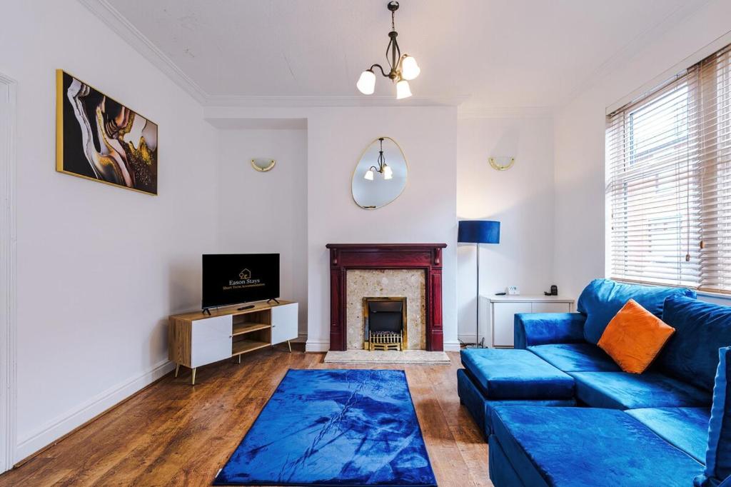 Una sala de estar con un sofá azul y una chimenea. en 3 BDR House By Eason Stays Short Lets Preston, en Penwortham