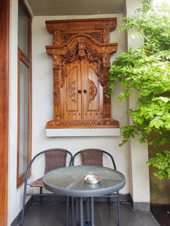 ein Tisch und zwei Stühle auf einer Terrasse mit einer Holztür in der Unterkunft Tropical Homestay of Balirejo in Demangan