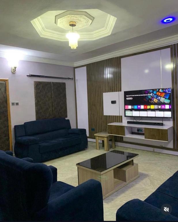 a living room with two blue couches and a flat screen tv at PnK Inn in Adeleye