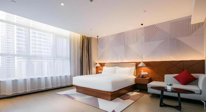 a bedroom with a bed and a couch and a window at Borrman Hotel Xi'an North High-speed Railway Station in Xi'an