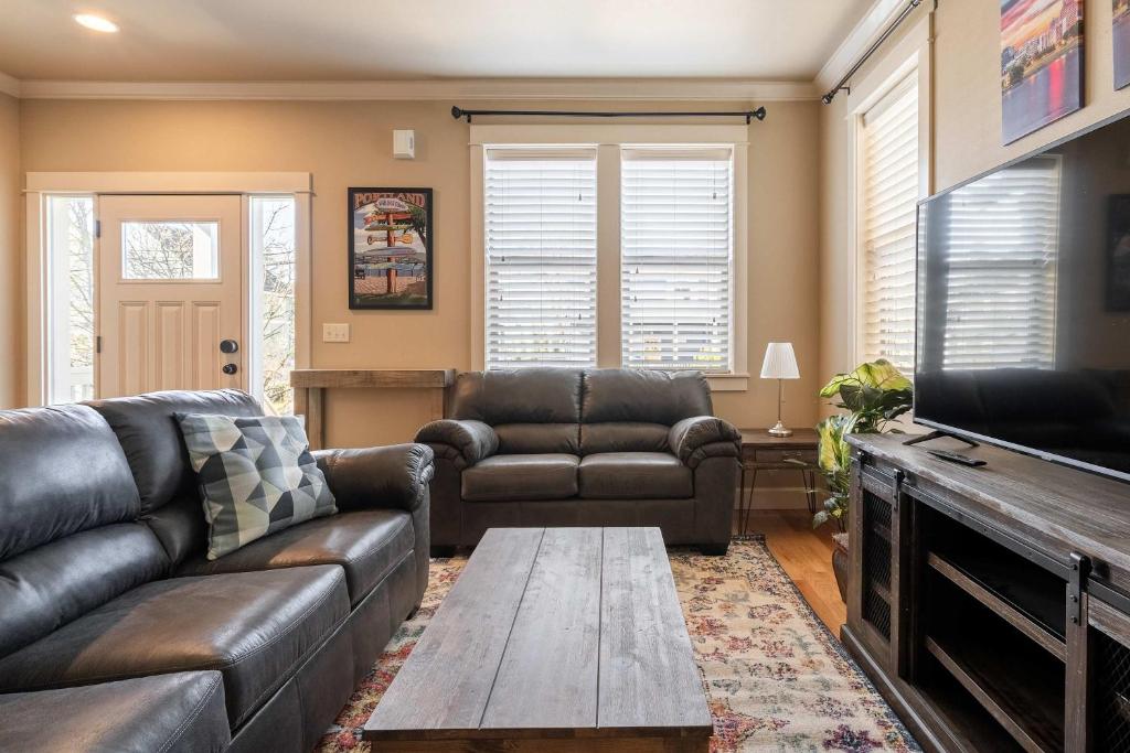 a living room with a leather couch and a table at Garfield 2BR - New Build - Foodie-Friendly Stay in Portland