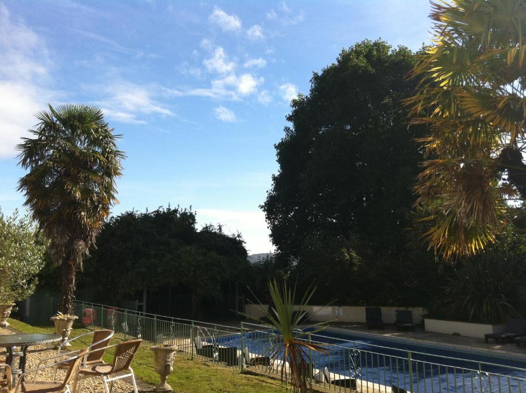 a pool with chairs and palm trees in a yard at Fernhill Hotel in Lyme Regis