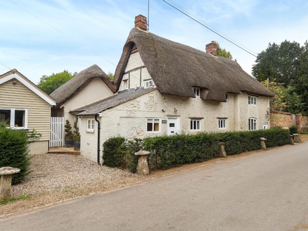 an old white house with a thatched roof at Lynchets Cottage in Lambourn