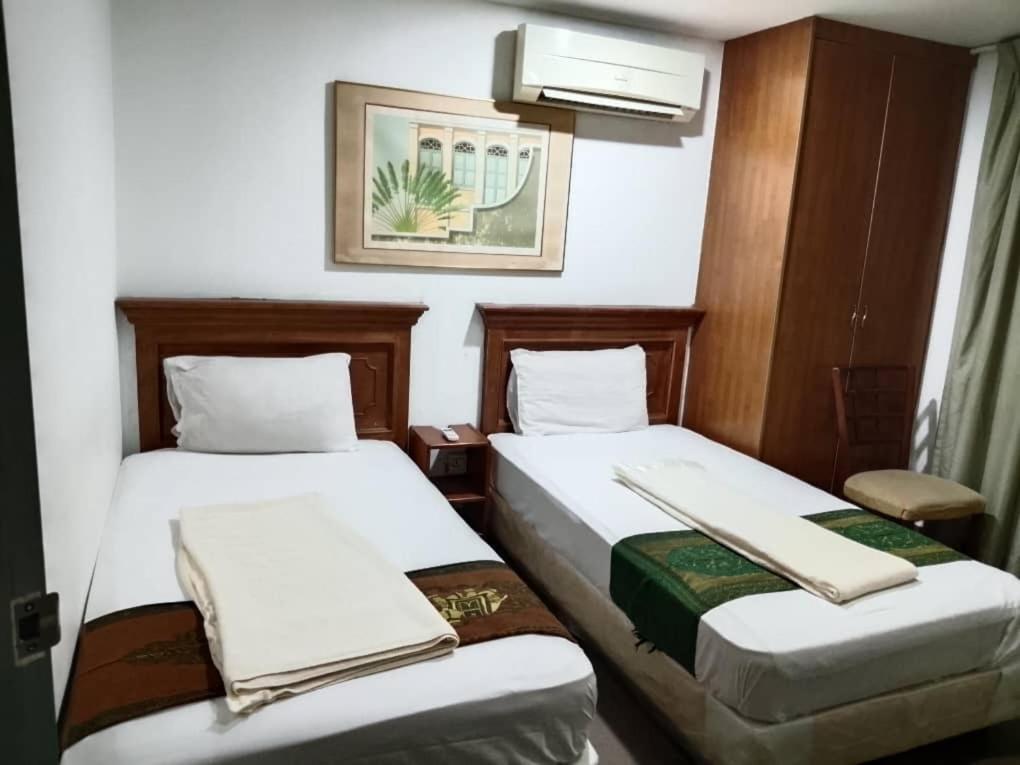 two beds in a hotel room with white sheets at J Hotel Bukit Bintang in Kuala Lumpur