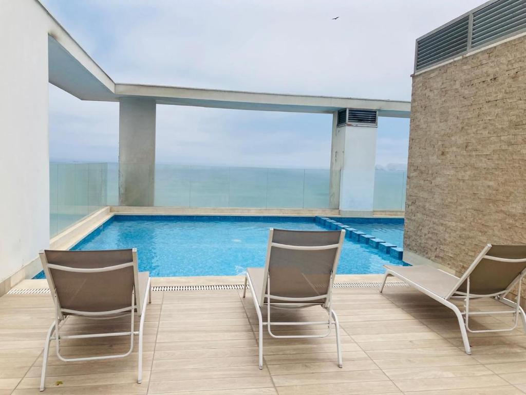 two chairs and a swimming pool on a building at San Miguel Apartment Ocean Magic in Lima