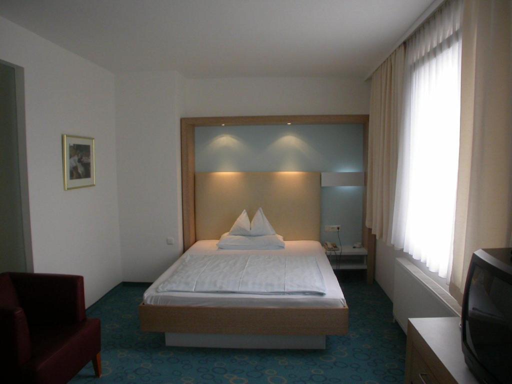 ein Hotelzimmer mit einem Bett in einem Zimmer in der Unterkunft Dom Hotel in Linz