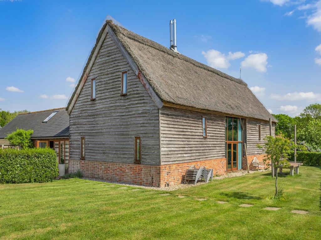an old barn with a grass yard in front of it at Liston Hall Barn in Gosfield