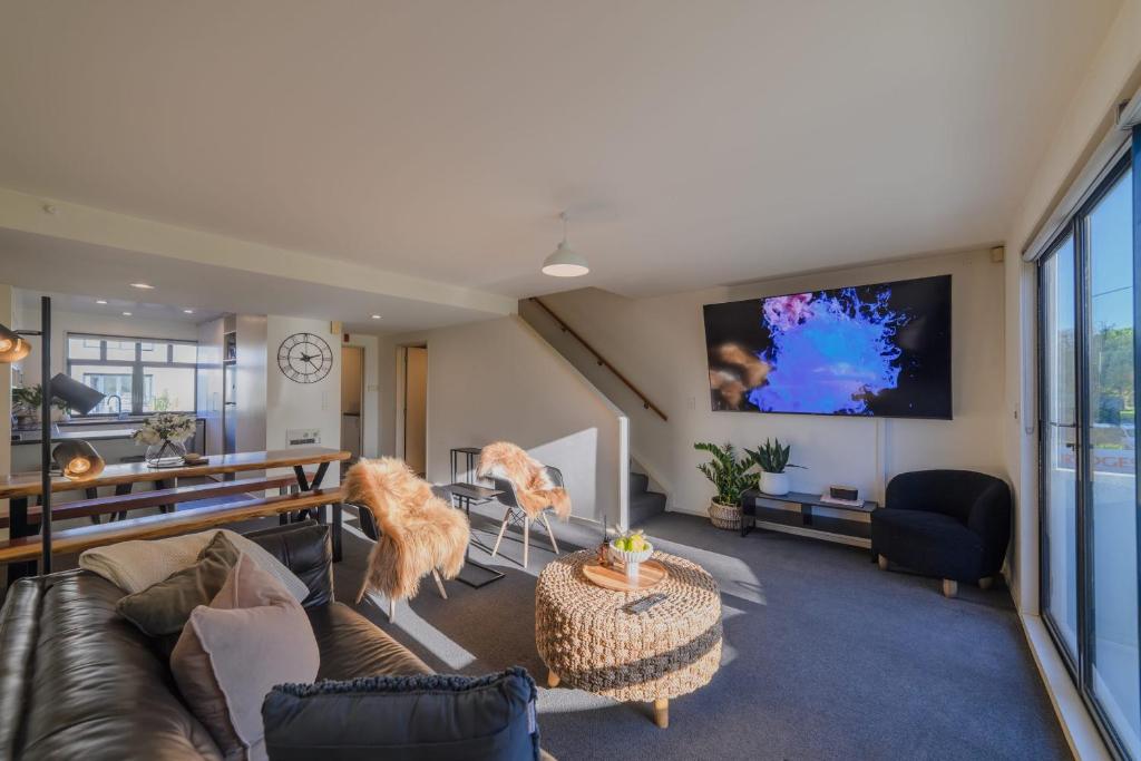 a living room with a couch and a flat screen tv at Elegant 3-Storey Townhouse with Garage Parking by Latimer Sq in Christchurch