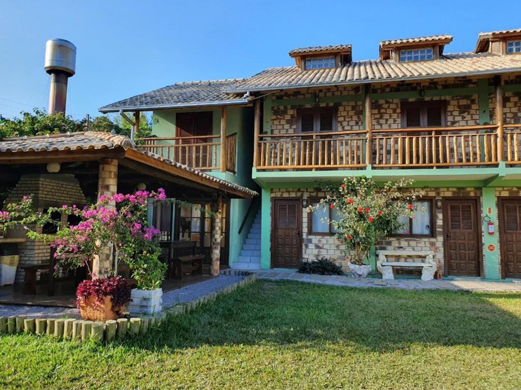 a house with a balcony and flowers in the yard at Território da Paz Pousada na Praia da Ferrugem in Garopaba
