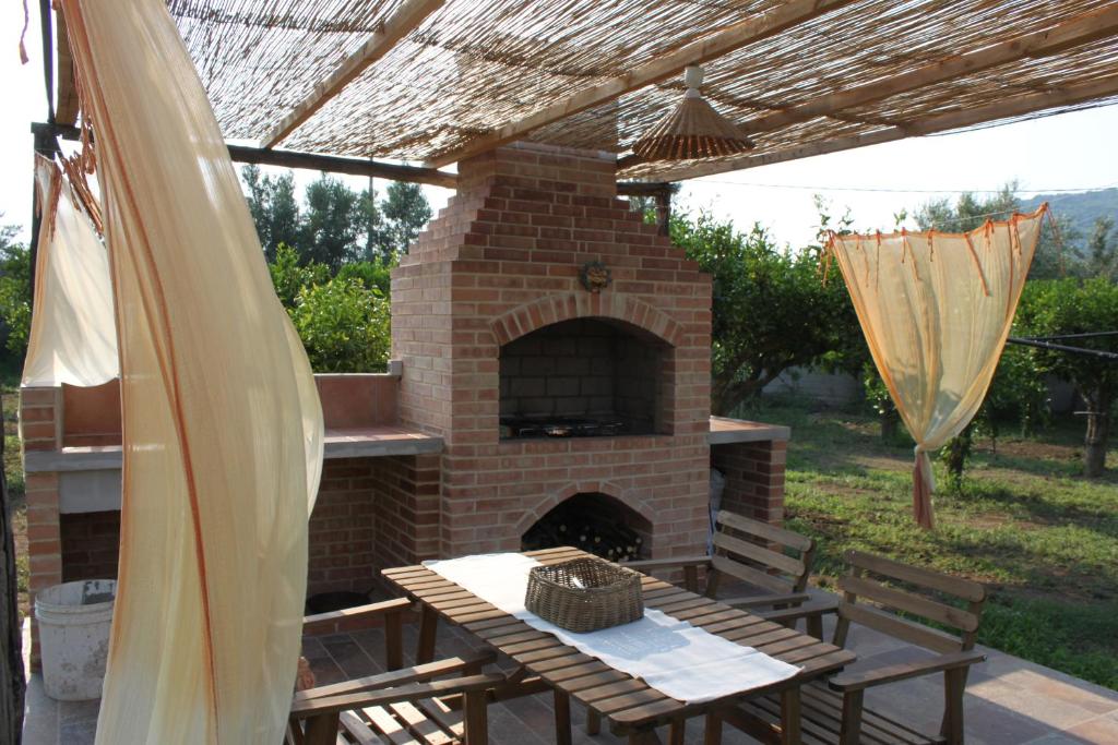 d'une terrasse avec un four en briques, une table et des chaises. dans l'établissement Agriturismo Le Terre Di Zoe', à Limbadi