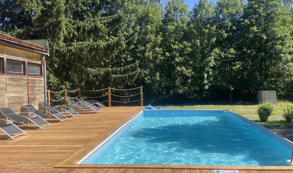 una piscina con sillas y una terraza de madera en Quiet Anomaly Glamping Forest & Wellness Retreat Adults Only, en Pirkenhammer