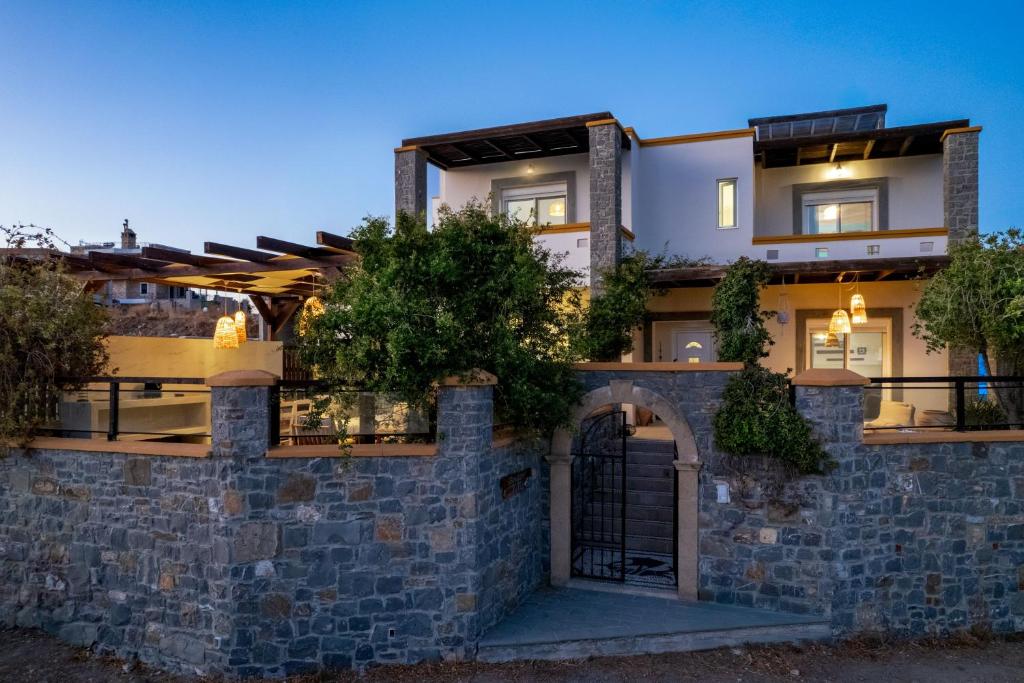 a stone wall with a gate in front of a building at Bougan Villa in Lartos