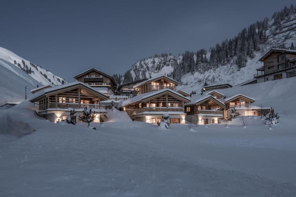 un lodge en la nieve por la noche con luces en Aadla Walser-Chalets mit privater Sauna, Hotpot und Hotelservice, en Schröcken