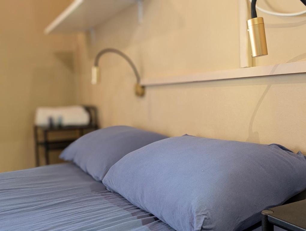 a bed with two blue pillows and a lamp at בקצה השמים in Bar Yohai