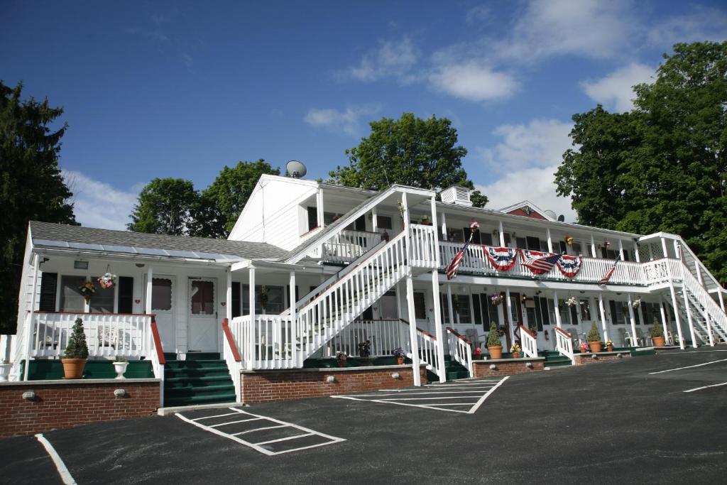 a white building with a staircase in a parking lot at Bennington Motor Inn in Bennington
