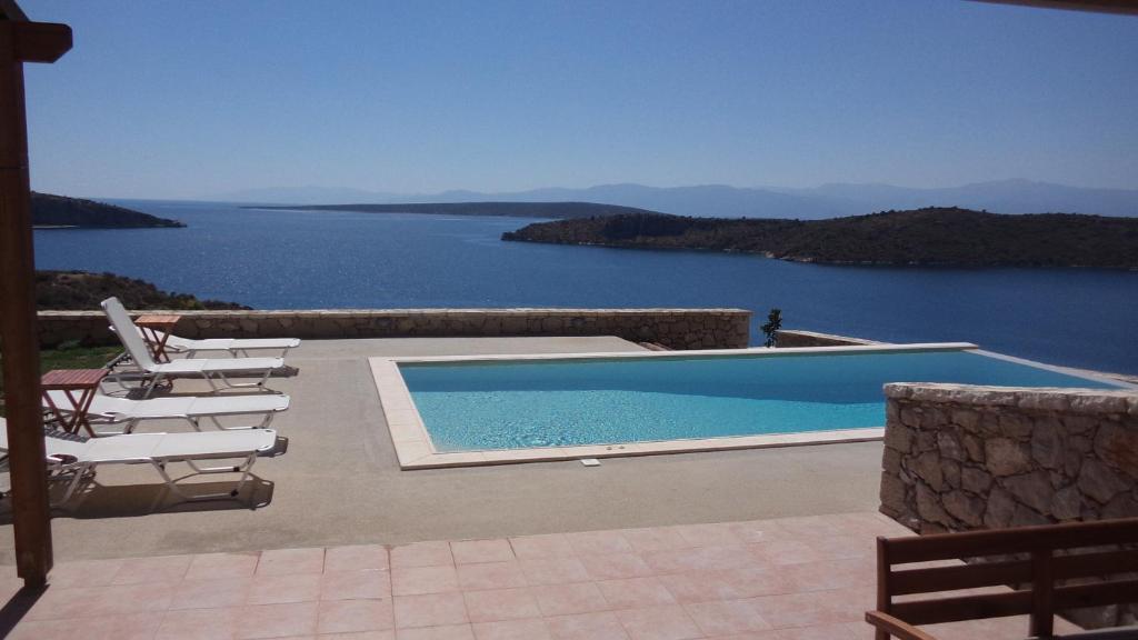 a swimming pool with chairs and a view of the water at Lefka's Villas in Vivari