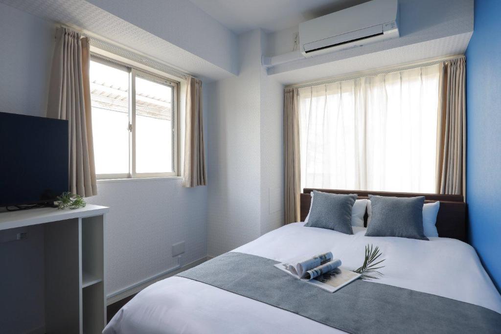 una camera da letto con un letto con televisore e asciugamani di Smart VILLA Hatanodai I a Tokyo