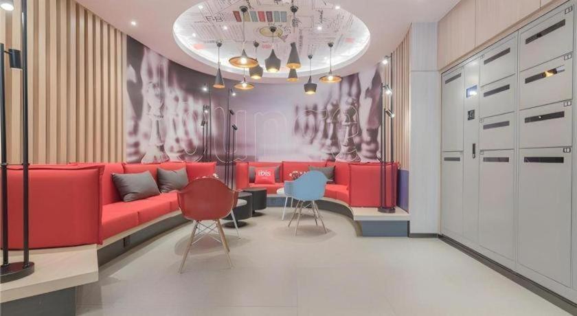 un salon avec un canapé rouge et deux chaises dans l'établissement ibis Chengdu East Railway Station Hotel, à Chengdu