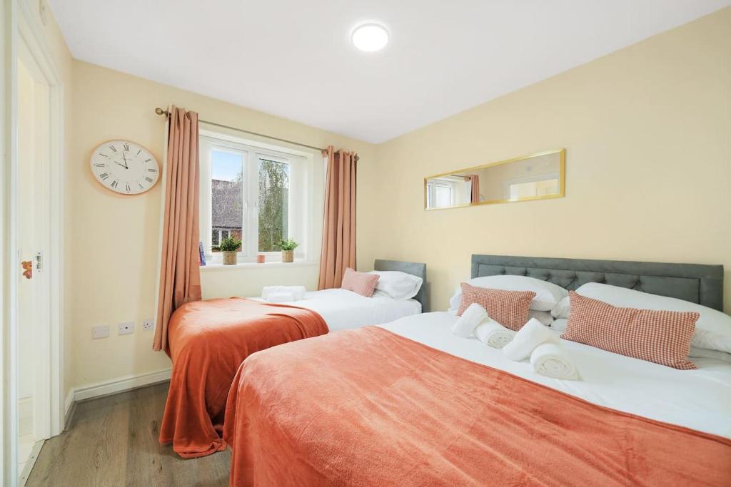 2 letti in una camera con orologio a parete di 3 BR 5 Beds 3 Bath Private Garden Parking x2 Ideal for Family & Work Stays ad Amersham