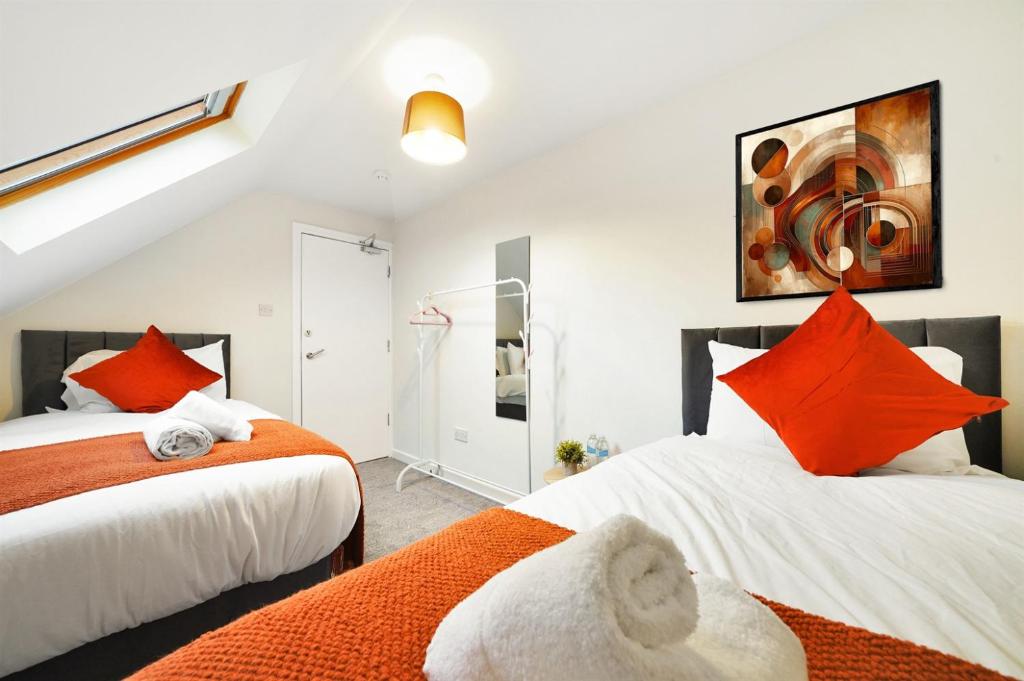 two beds with orange pillows in a bedroom at King Size beds, CCTV parking , Discounts in Shinfield