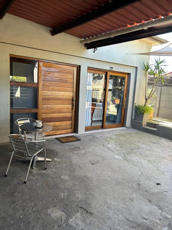 a patio with a table and a chair in front of a house at Mabel View in Cape Town