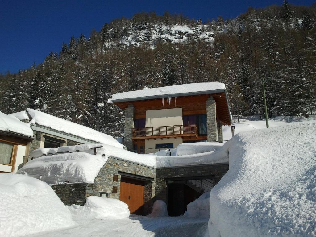 a building covered in snow with a mountain in the background at La Niche B&B in La Thuile