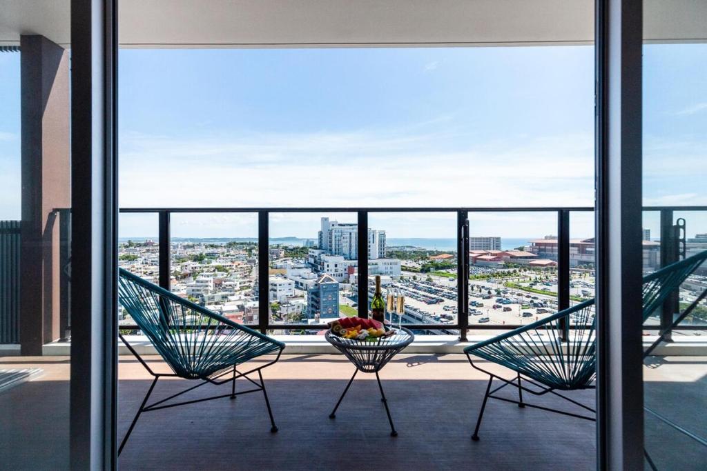 two chairs on a balcony with a view of a city at エンズプラザライカム1201 in Okinawa City