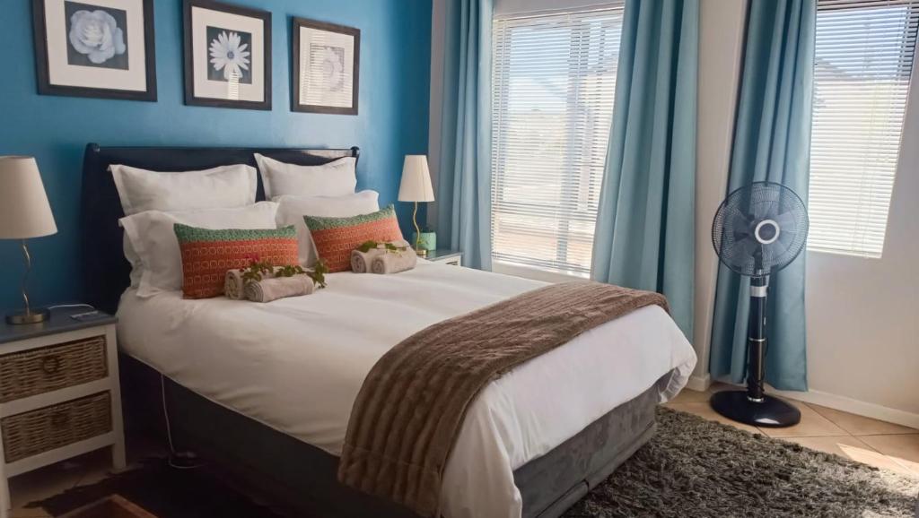 a bedroom with a large bed with blue walls and a fan at Creative 2 Level Townhouse Near City and Wine Route in Brackenfell