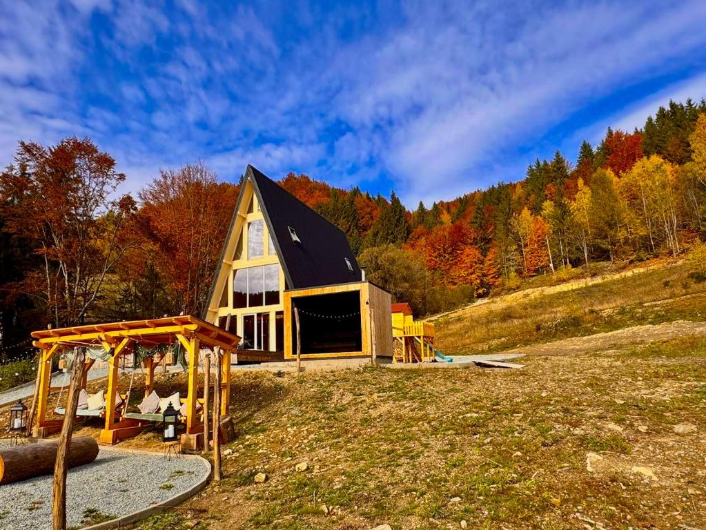 a small house in a field with a playground at Cabana KayLuna in Mătişeşti
