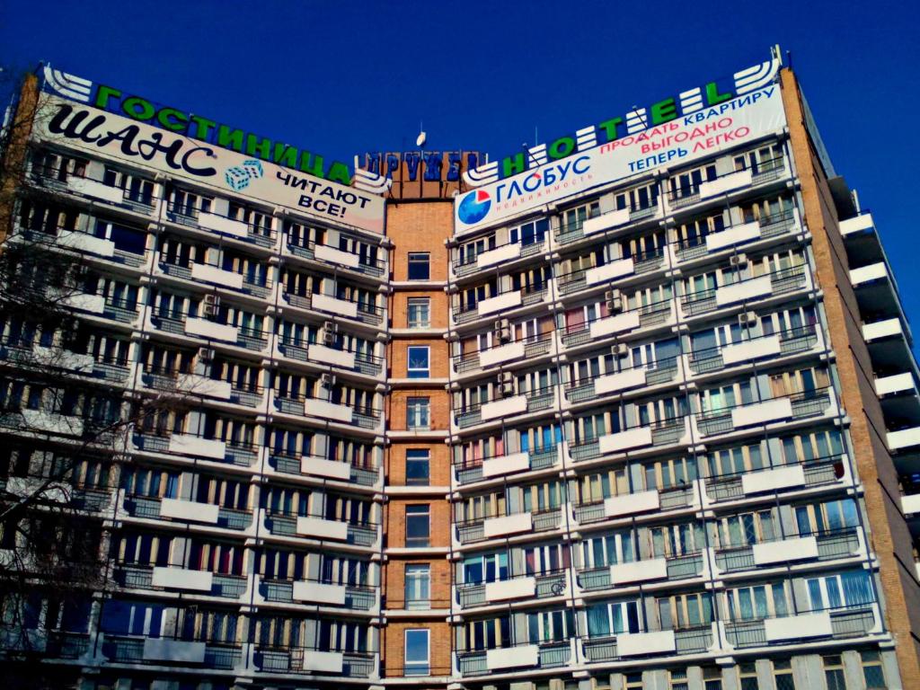 un edificio alto con muchas ventanas y señales en él en Hotel Druzhba, en Abakán