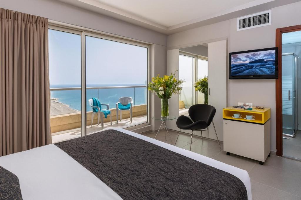 バト・ヤムにあるחדר על הים בבת יםの大きなベッドと大きな窓のあるホテルの部屋