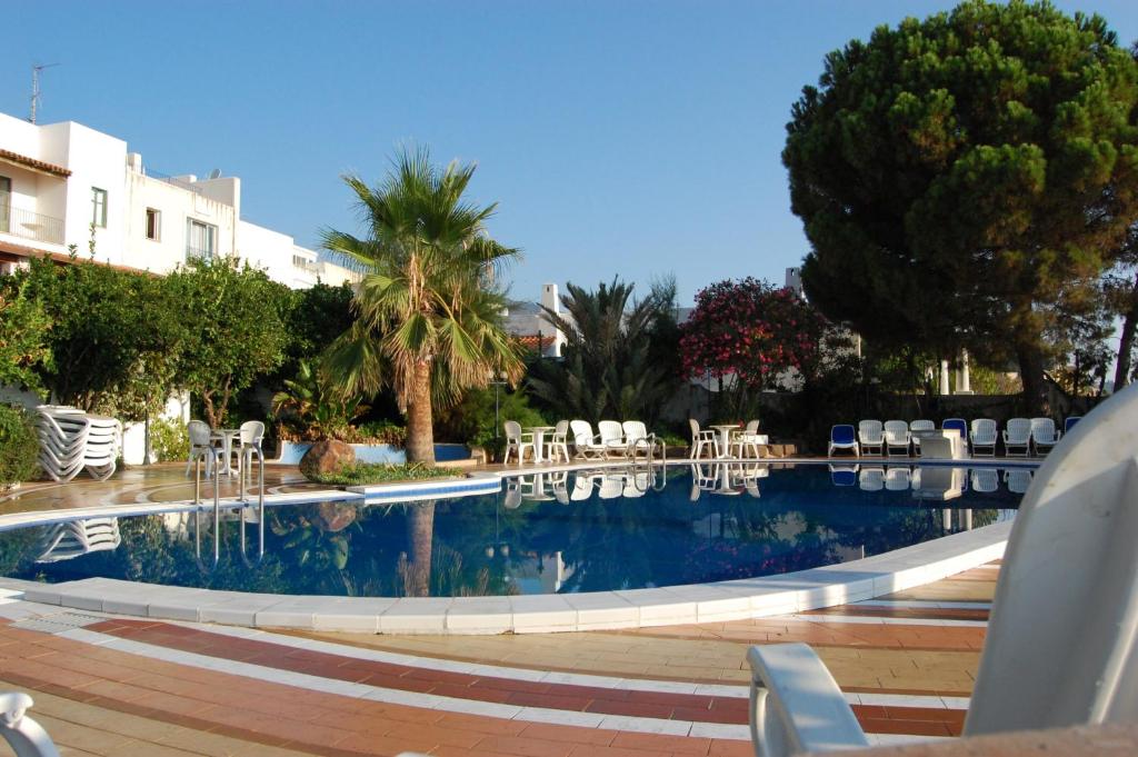 a swimming pool with chairs and tables and trees at Hotel Giardino Sul Mare in Lipari