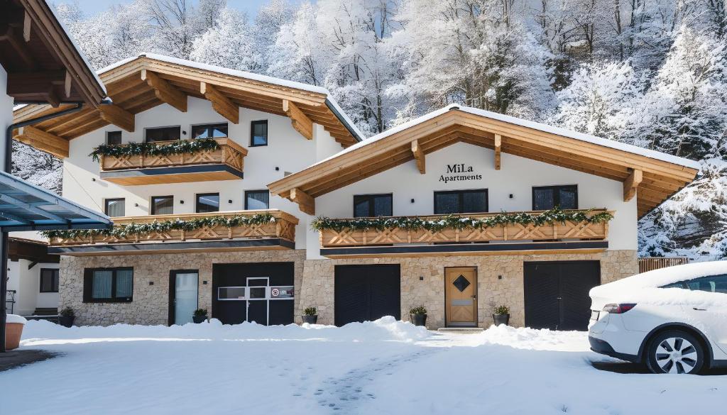 a building in the snow with a car parked in front at MiLa Apartments in Saalbach Hinterglemm