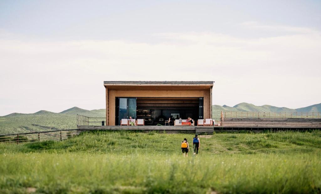two people standing in a field in front of a building at Yeruu lodge in Jargalant