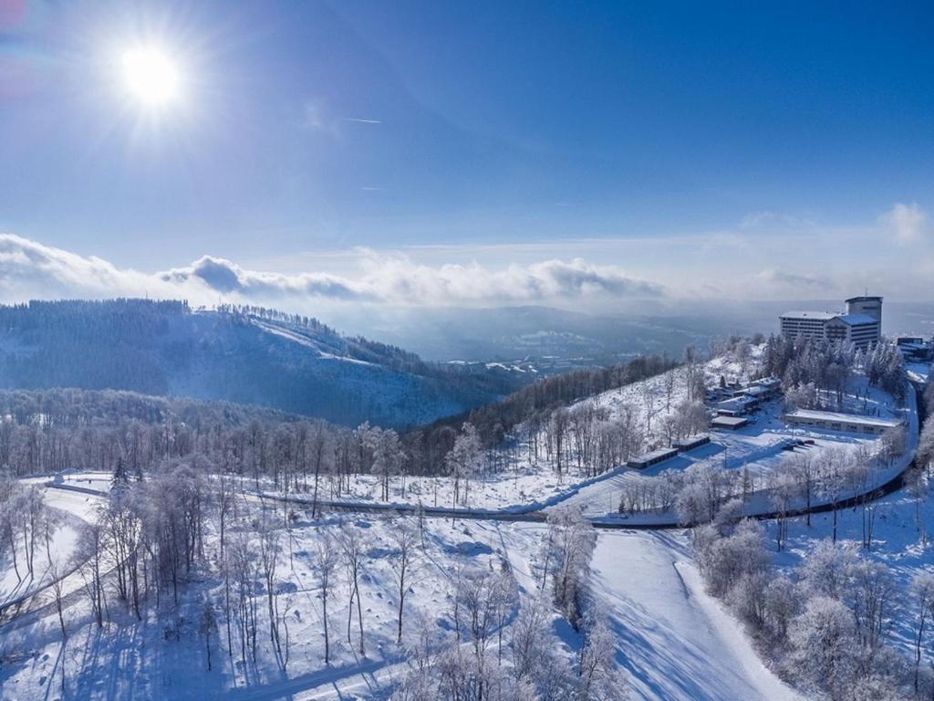 a view of a snowy mountain with the sun in the sky at Ringberg Hotel in Suhl