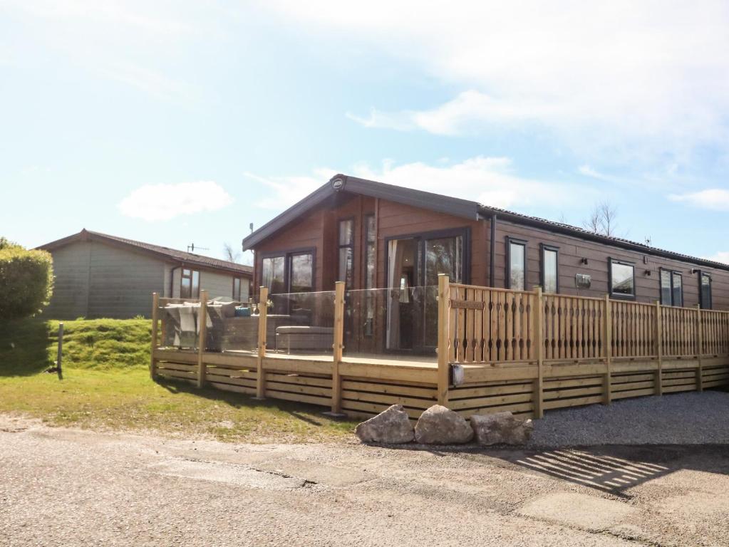 a wooden cabin with a fence and a house at Curlew Lodge in Carnforth