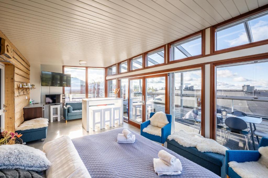 a room with two beds and a living room with windows at Hotel Arctic Zone in Ruka