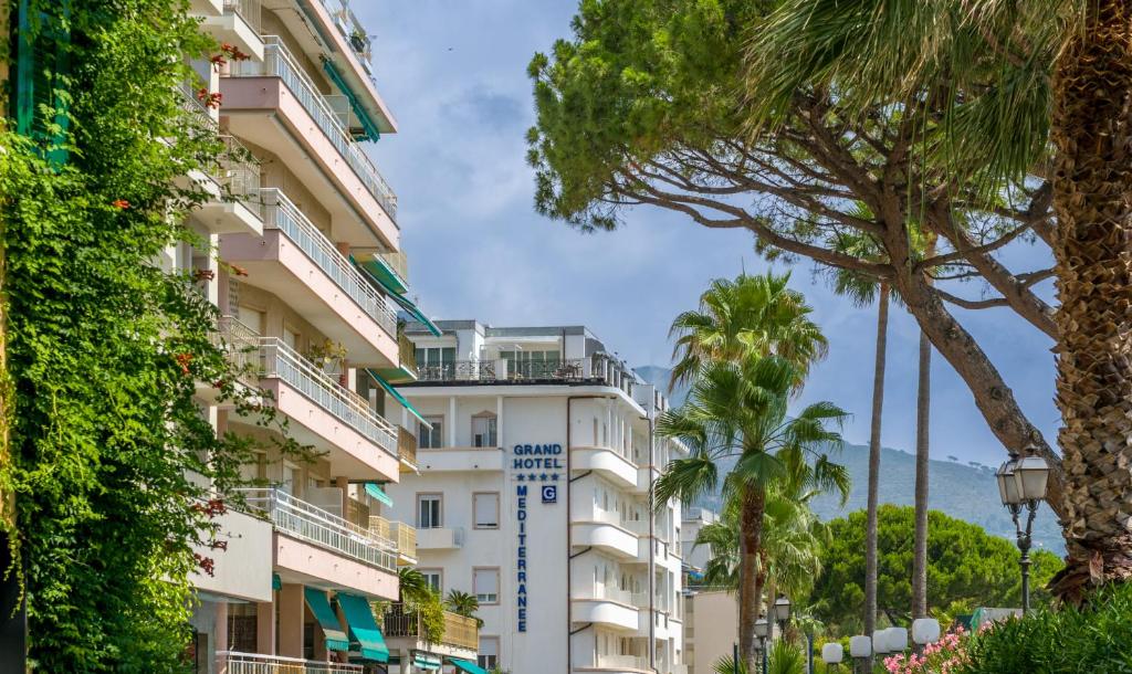 a building with palm trees in front of it at Grand Hotel Mediterranee in Alassio