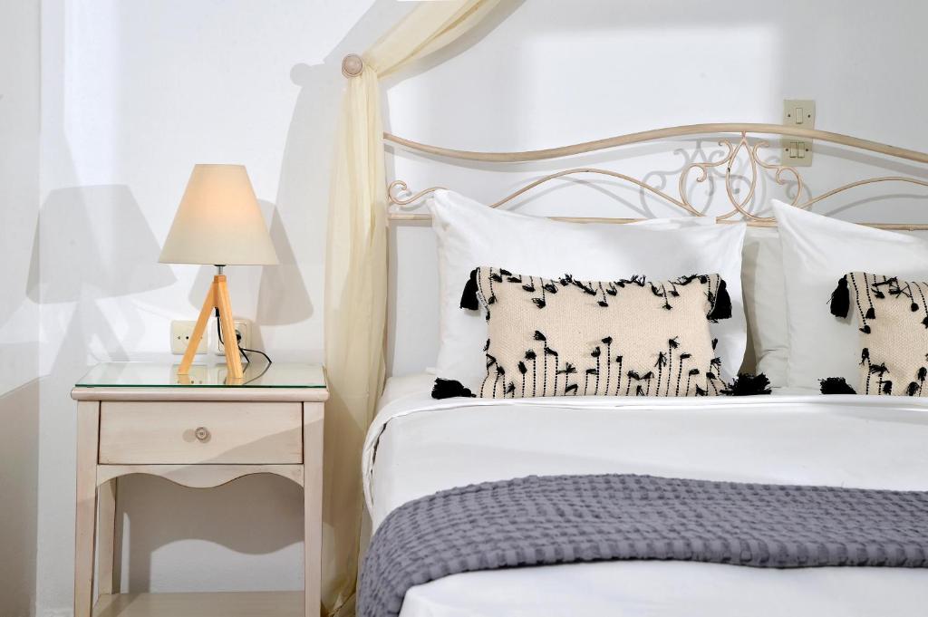 a bedroom with a white bed and a nightstand with a lamp at Vasilaras Hotel in Skala