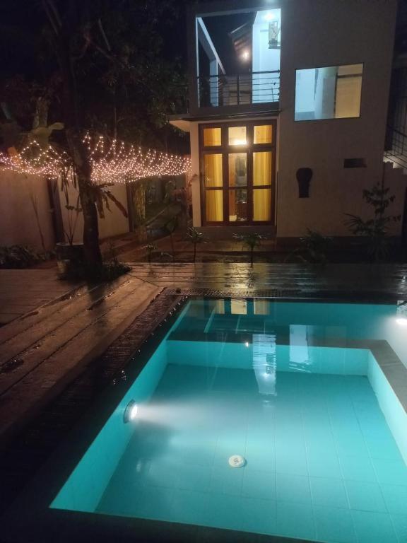 a swimming pool in front of a house at night at Green villa in Galle