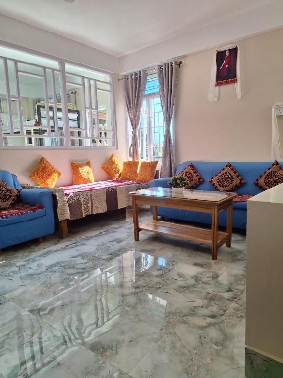 a living room with a blue couch and a table at TN's Basecamp Hostel in Tawang