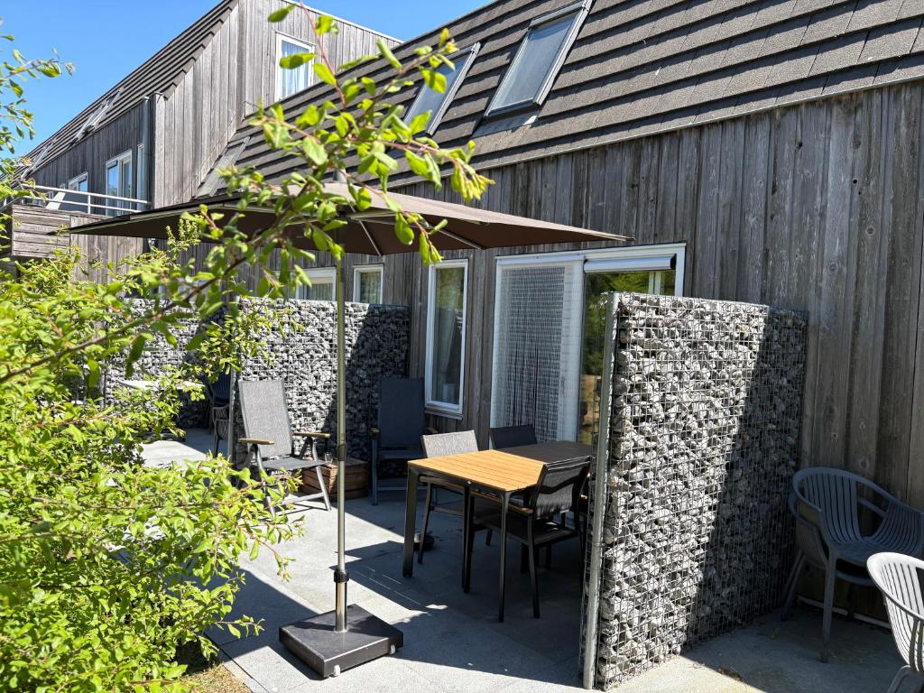 Un patio con una mesa y sillas y una sombrilla. en Strand 104, en Hollum