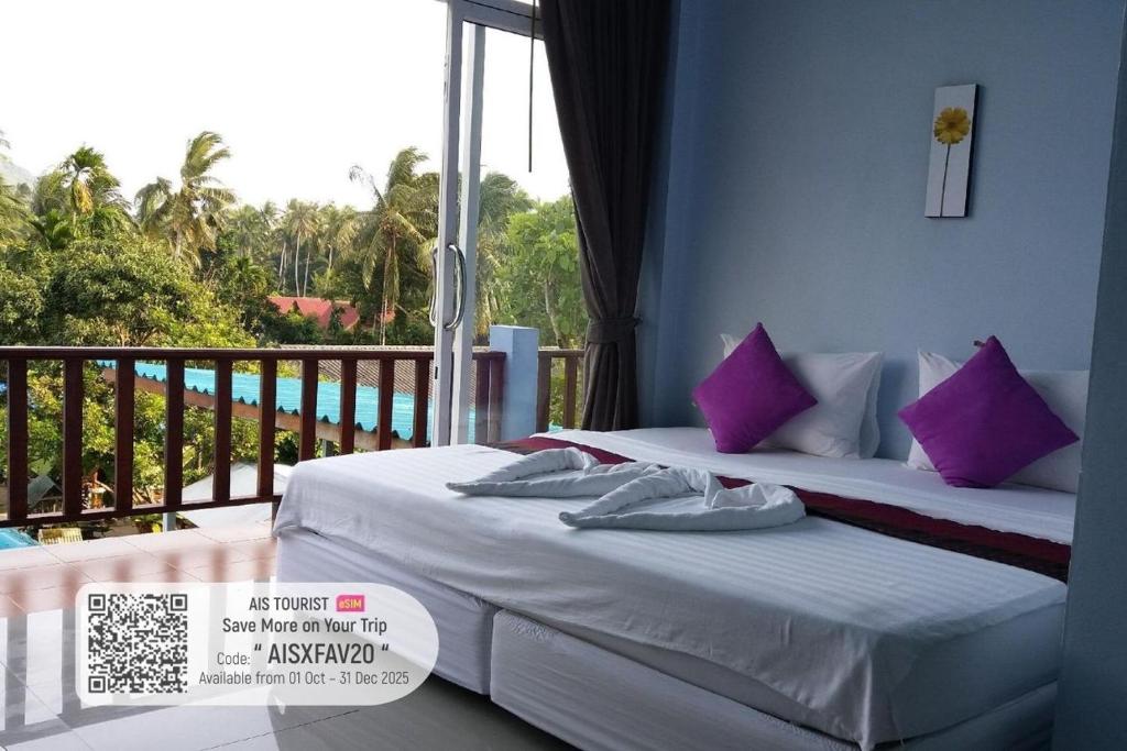 two beds with purple pillows in a room with a balcony at Hotel Rung Phangan in Baan Tai