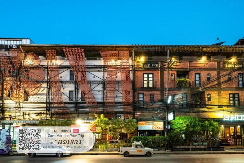 a white car parked in front of a building at The 8 Factory Hotel Phitsanulok in Phitsanulok
