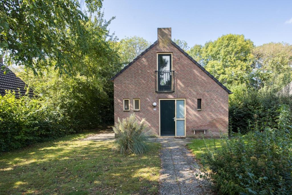 une vieille maison en briques avec une fenêtre et une porte dans l'établissement Zonnige luxe bungalow met grote tuin, à Ewijk