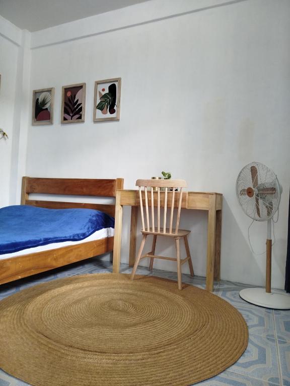 a bedroom with a bed and a chair and a fan at Hamada's Guesthouse in Baler