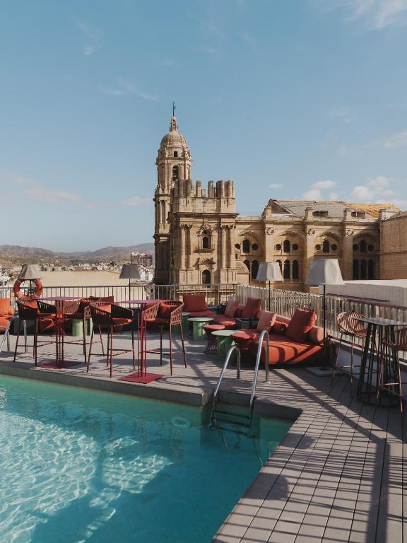 a pool with chairs and tables and a building at Catalonia Molina Lario in Málaga