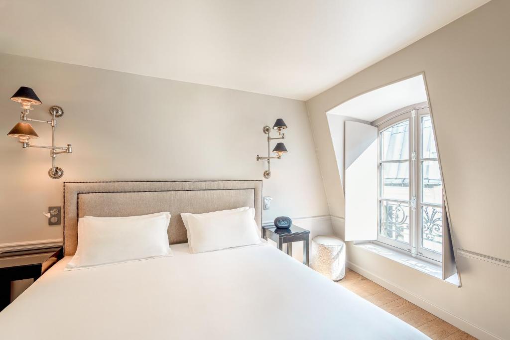 パリにあるHotel Résidence Des Arts - Saint-Germainの大きな白いベッドと窓のある寝室