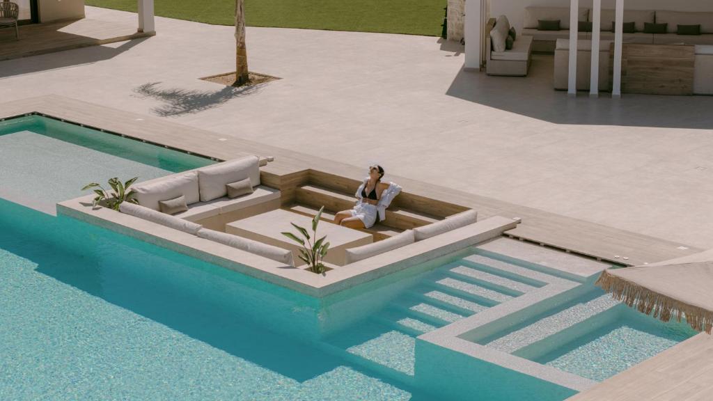 a woman sitting on a couch in the middle of a pool at Anassa Villa, with 110m2 Pool, Emerald Gardens, Wellness & Sports, By ThinkVilla 