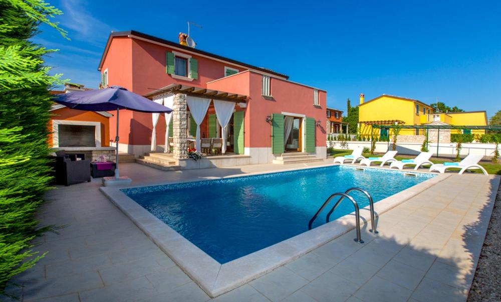 ein Haus mit einem Pool vor einem Haus in der Unterkunft Villas Vilanija in Umag